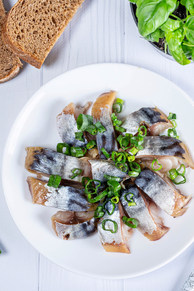 Куски скумбрии на столе с луком, хлебом и базиликом