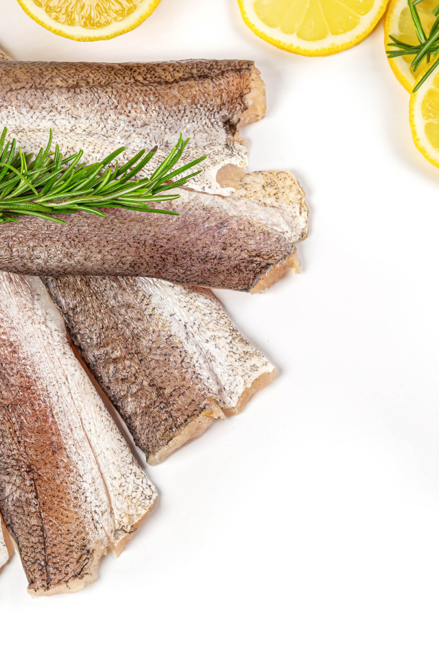 Сырая рыба с розмарином и лимоном на белом фоне