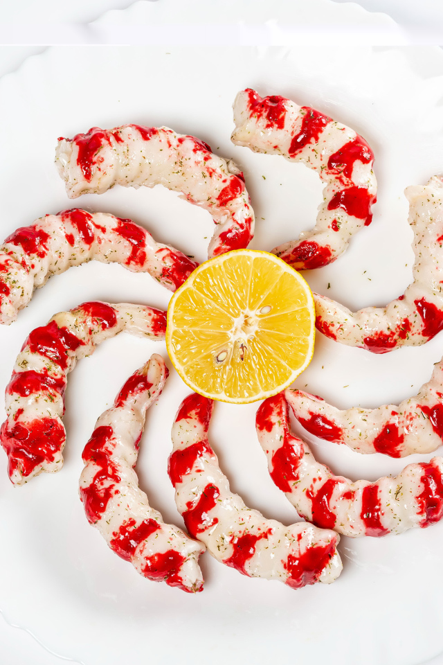 Тигровые креветки на тарелке с лимоном на белом фоне 