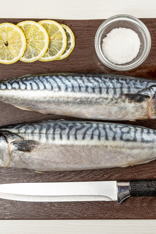 Две свежие скумбрии на доске с лимоном 