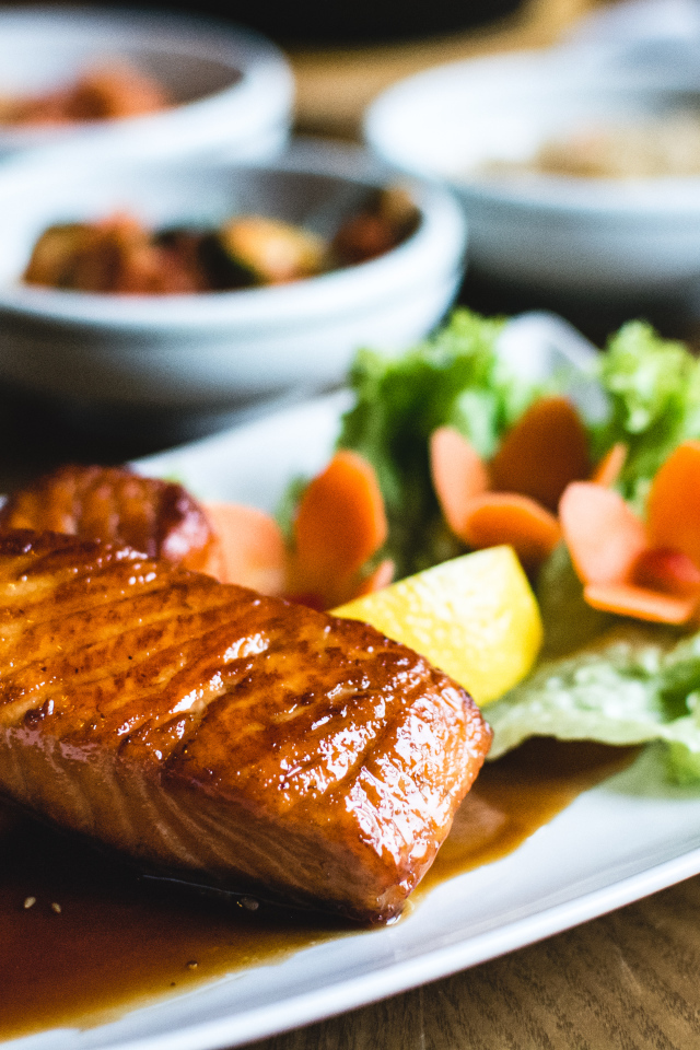 Два куска рыбы в соусе с овощами на тарелке