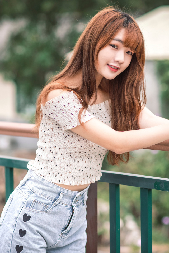 Красивая девушка азиатка стоит у перил у дома