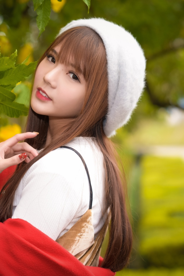 Девушка в берете стоит у куста с желтыми цветами