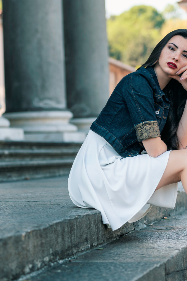 Девушка в белом платье сидит на ступеньках