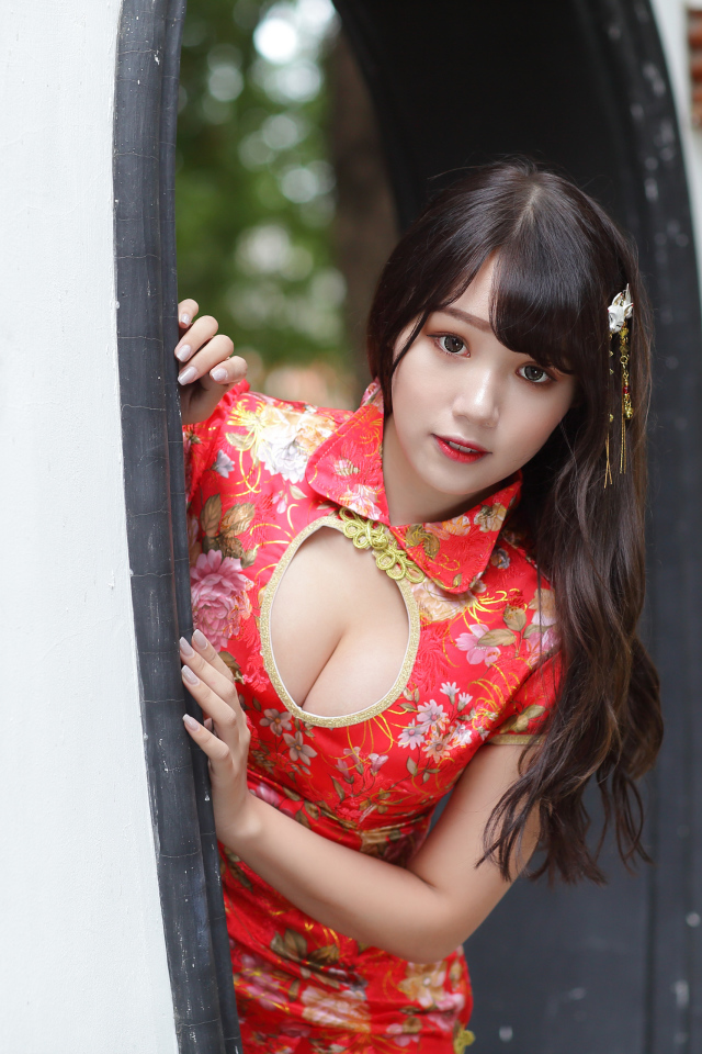 Девушка азиатка в красном платье стоит в арке