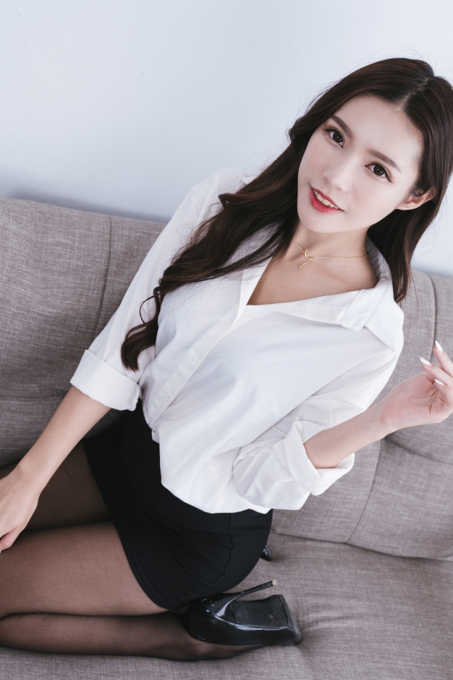Девушка азиатка в белой рубашке на диване 