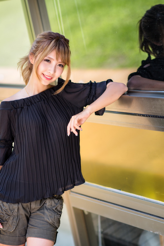 Девушка азиатка в черной блузке у окна