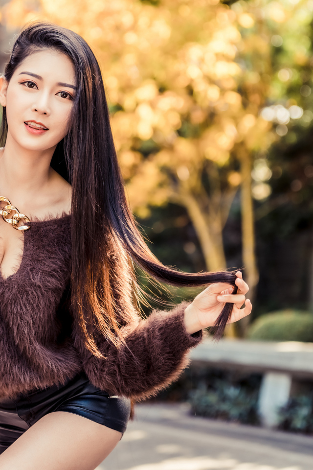 Девушка азиатка в черных шортах у стены