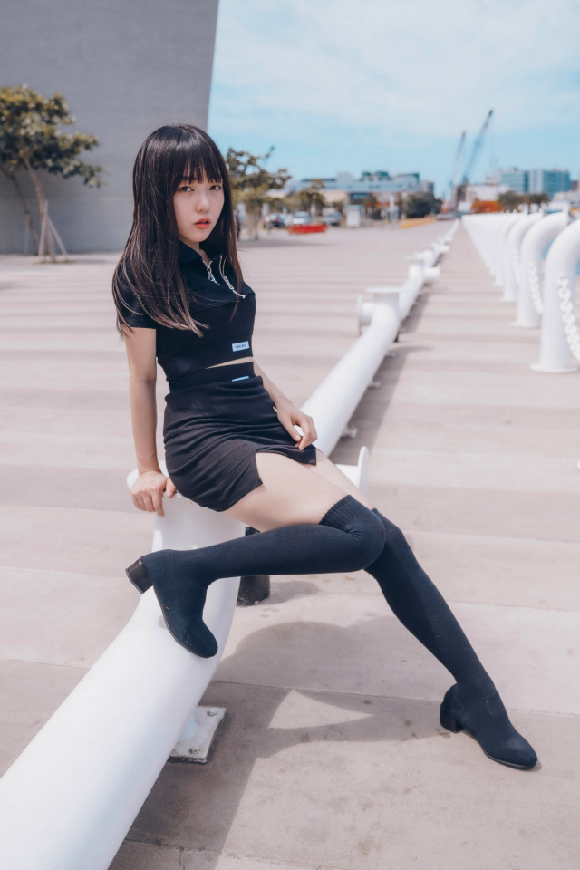 Девушка азиатка в черном костюме на пристани 