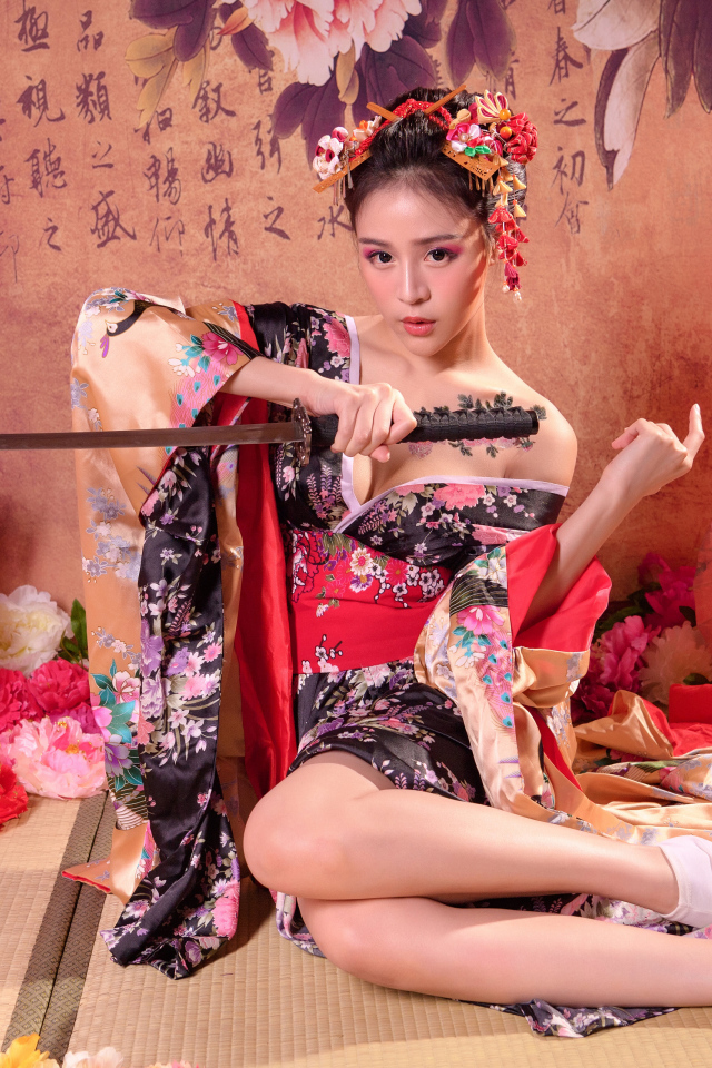 Девушка азиатка в кимоно с мечом сидит на полу 