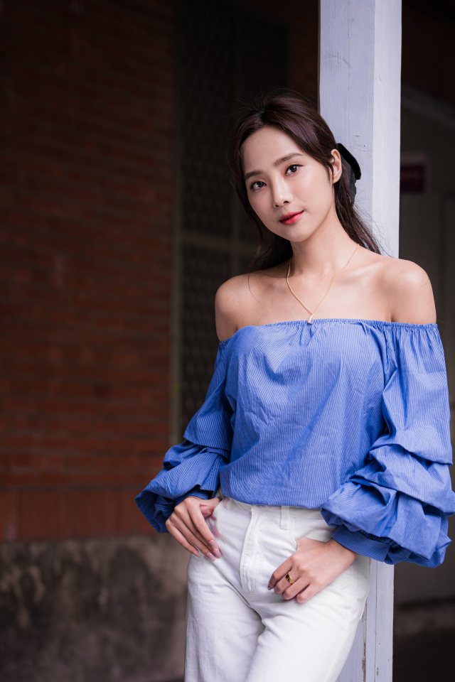 Девушка азиатка в белых брюках у дома