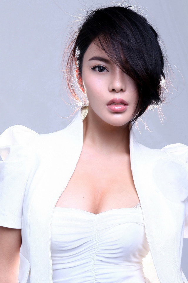 Девушка азиатка в белом костюме на сером фоне 