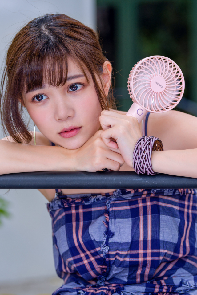 Девушка азиатка с вентилятором в руке 