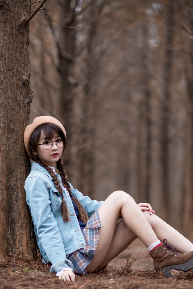 Девушка азиатка школьница сидит под деревом