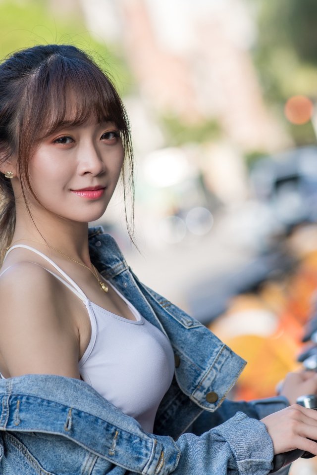 Красивая азиатка в джинсовой куртке с велосипедом