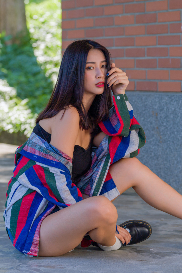 Красивая азиатка в рубашке у стены