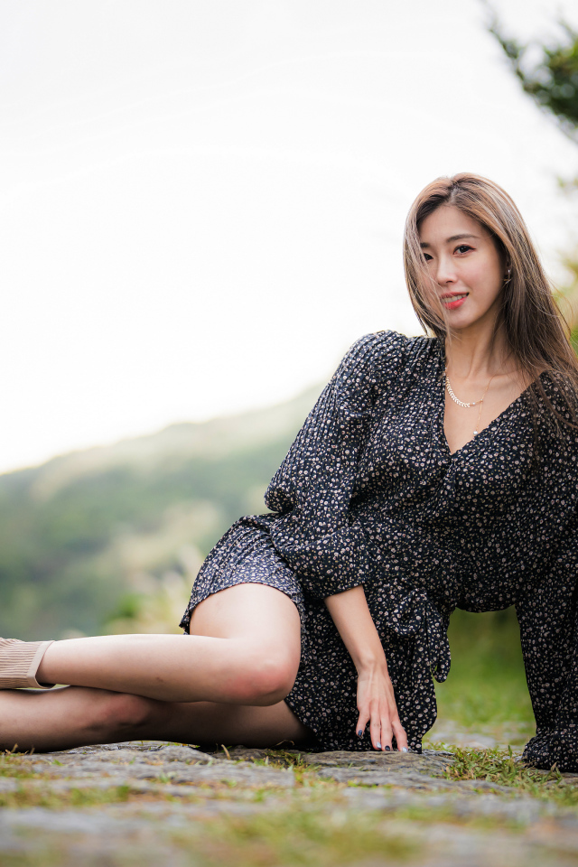 Красивая девушка азиатка в платье лежит на земле 