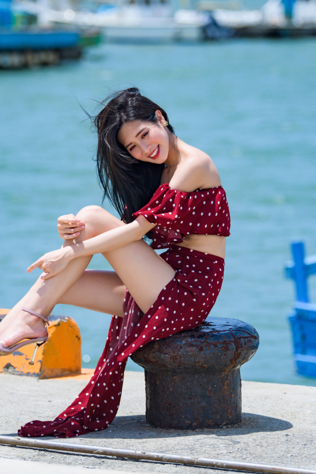 Красивая девушка азиатка в платье в горох у моря