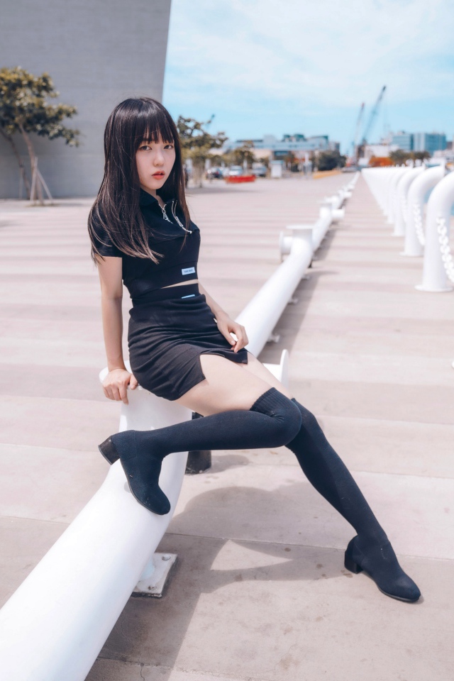 Красивая девушка азиатка в черных сапогах на причале