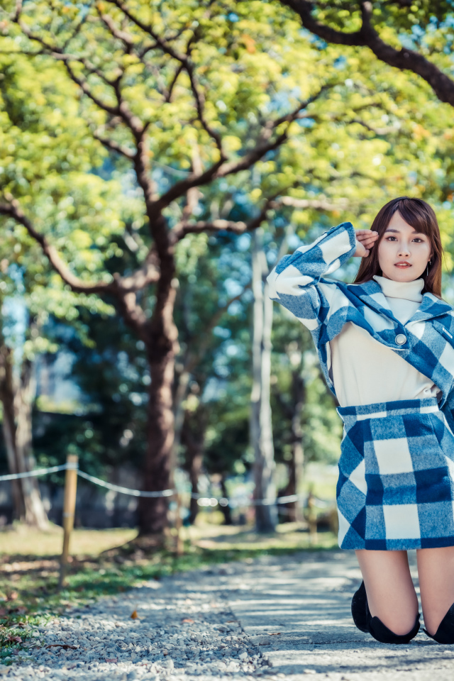 Красивая девушка азиатка стоит на коленях в парке