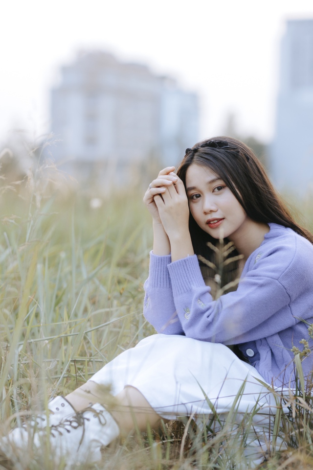 Красивая девушка азиатка сидит на поле с травой 