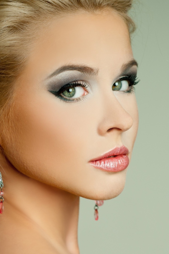 Красивая девушка блондинка с красивыми сережками на сером фоне