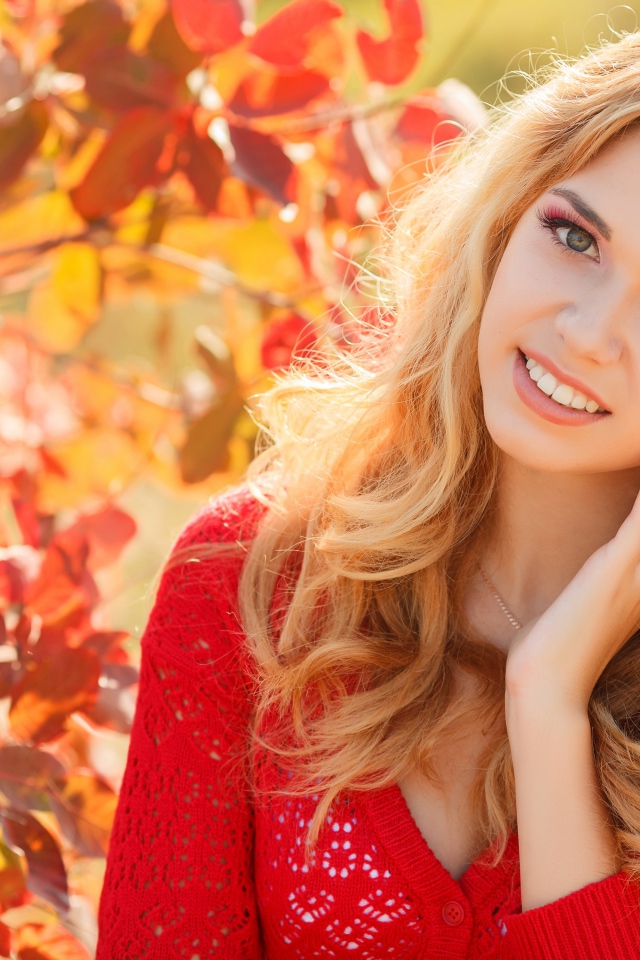 Красивая блондинка в красной кофте на улице осенью 