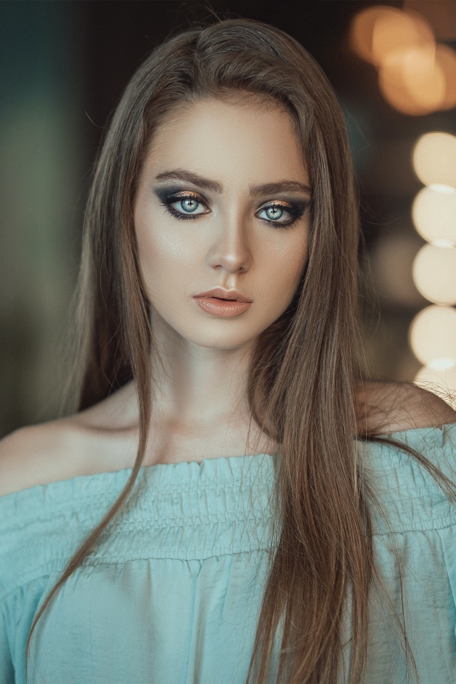 Красивая голубоглазая девушка в платье у зеркала 