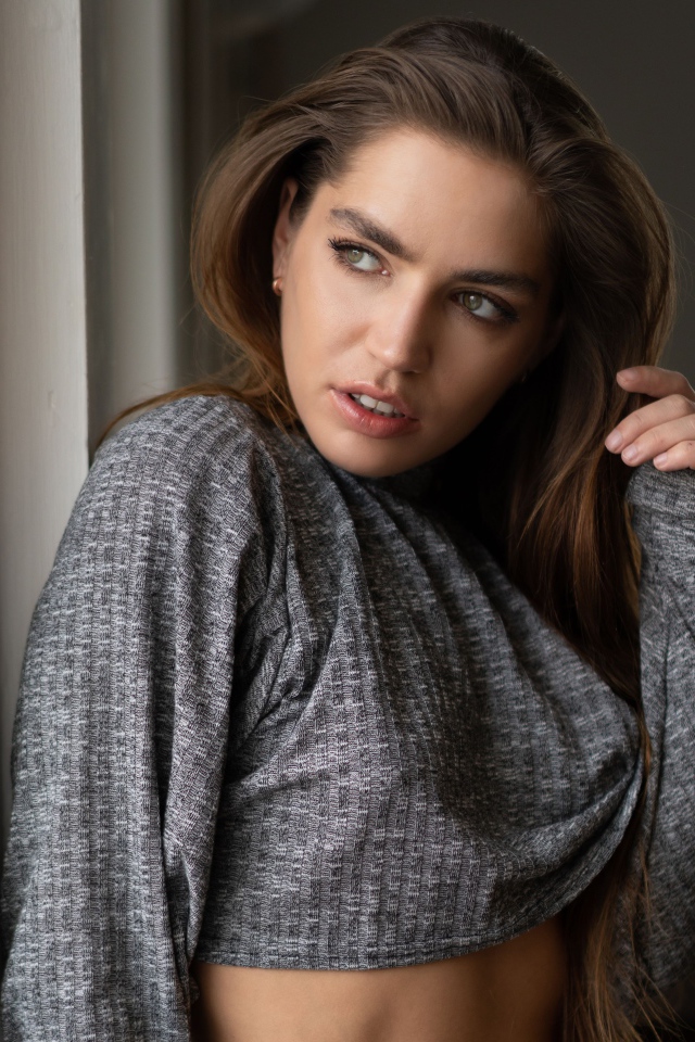 Красивая девушка брюнетка стоит у окна