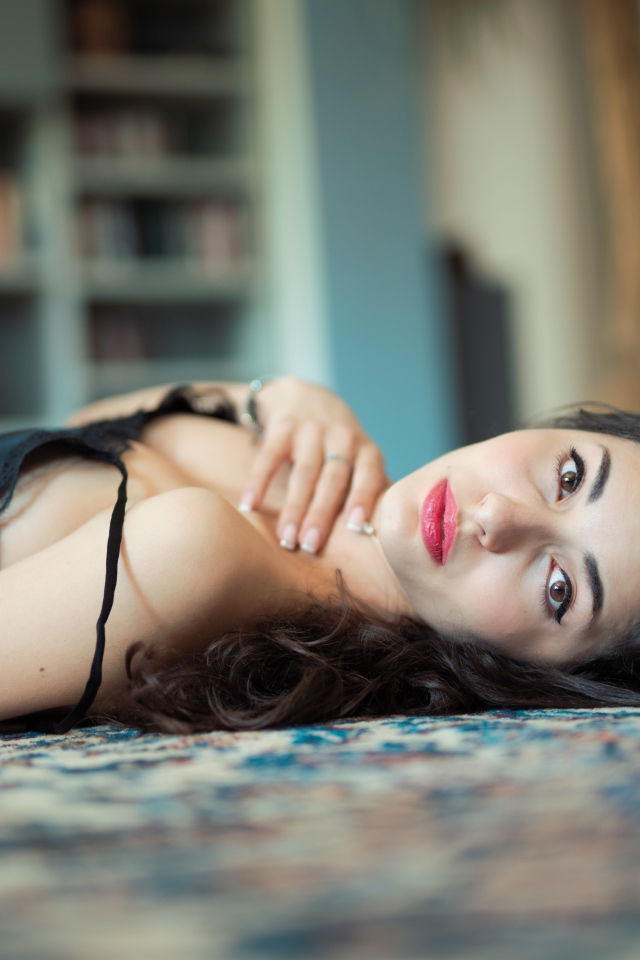 Красивая брюнетка в черном платье лежит на полу