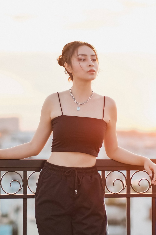 Красивая девушка в черном костюме на мосту в лучах солнца