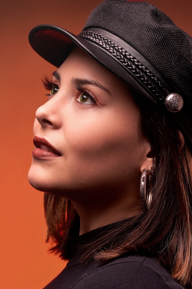 Красивая девушка в кепке на коричневом фоне