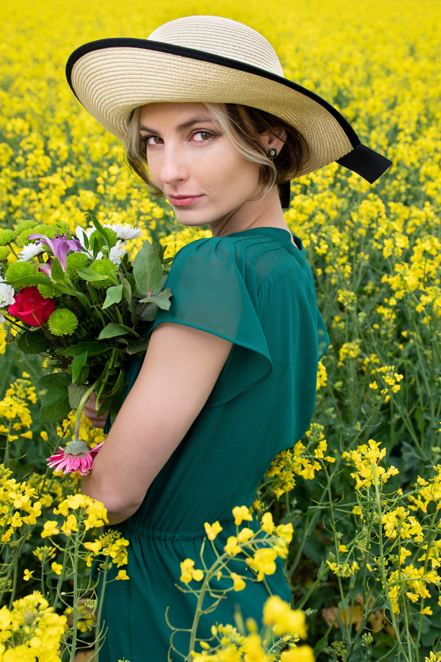Красивая девушка в шляпе на поле с желтыми цветами летом