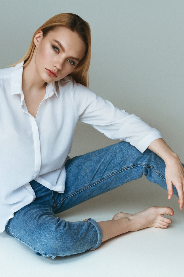 Красивая девушка в белой рубашке на сером фоне