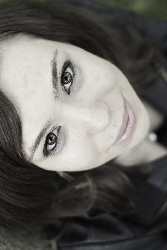 Красивая девушка смотрит вверх сидя под деревом  