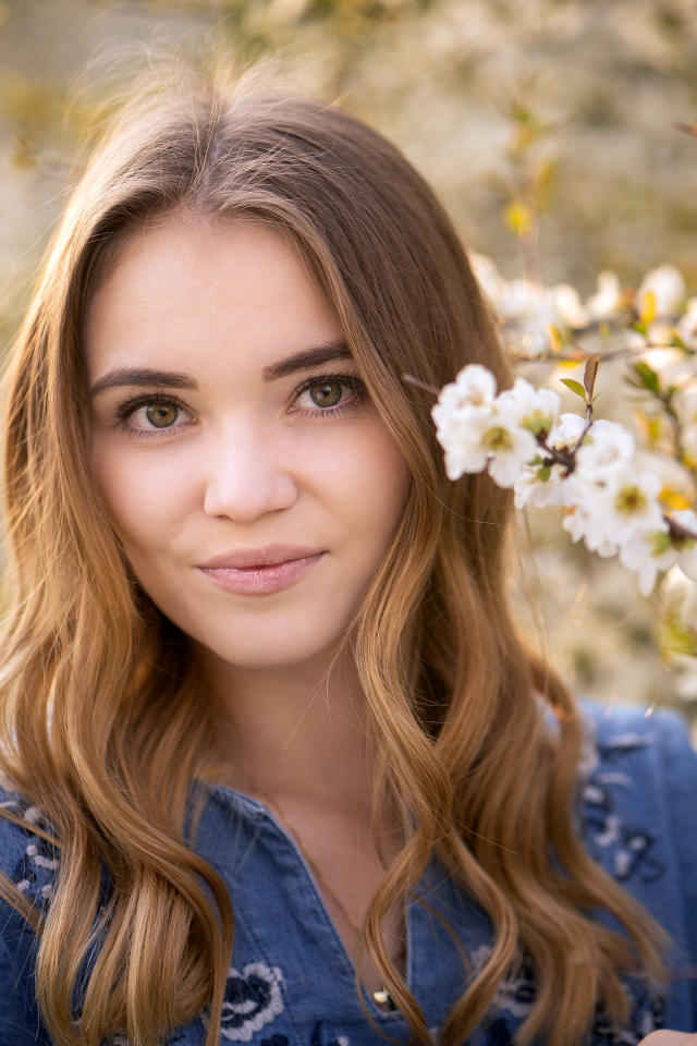 Красивая девушка у ветки с белыми цветами