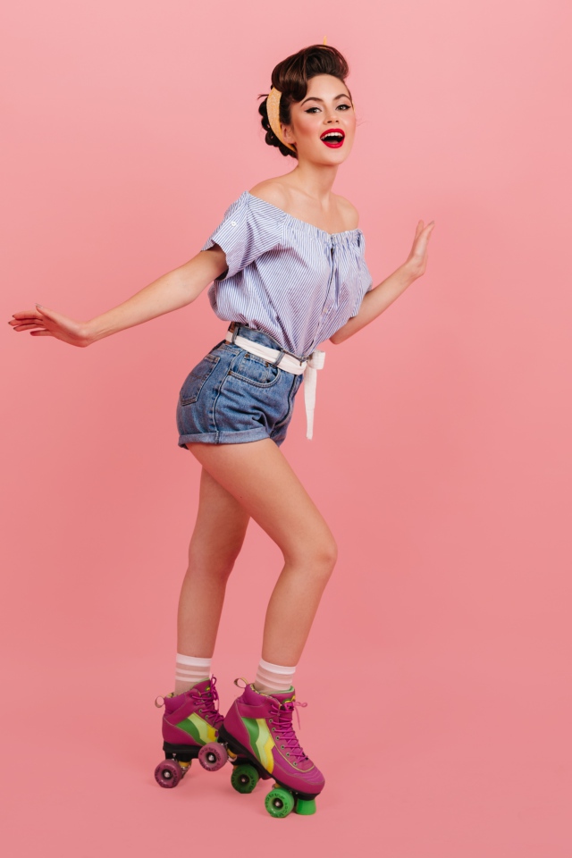 Красивая девушка на роликах на розовом фоне 