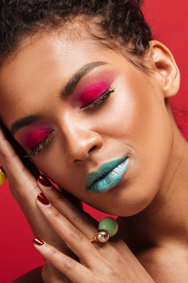 Красивая девушка с ярким макияжем на красном фоне