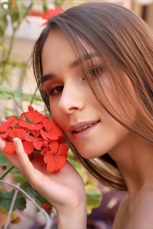 Красивая девушка с красным цветком герани 