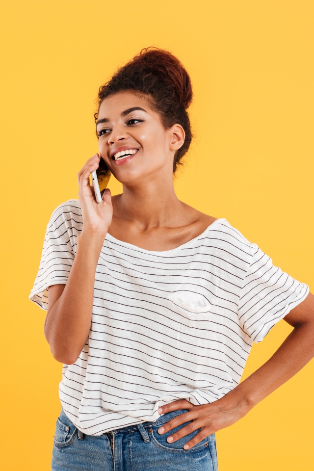 Красивая девушка со смартфоном на желтом фоне