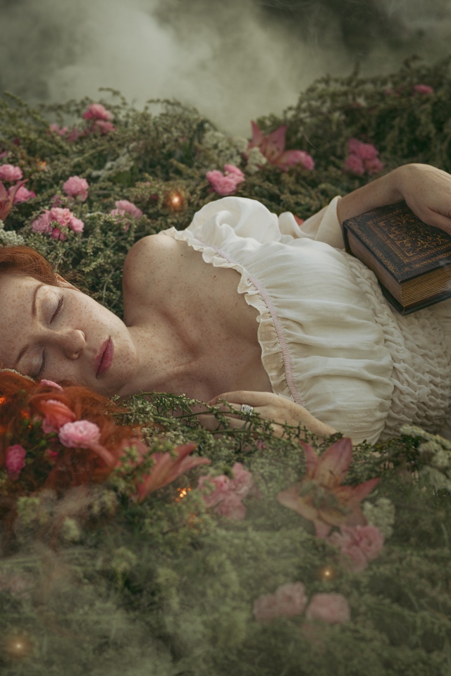 Красивая рыжеволосая девушка спит на земле с книгой