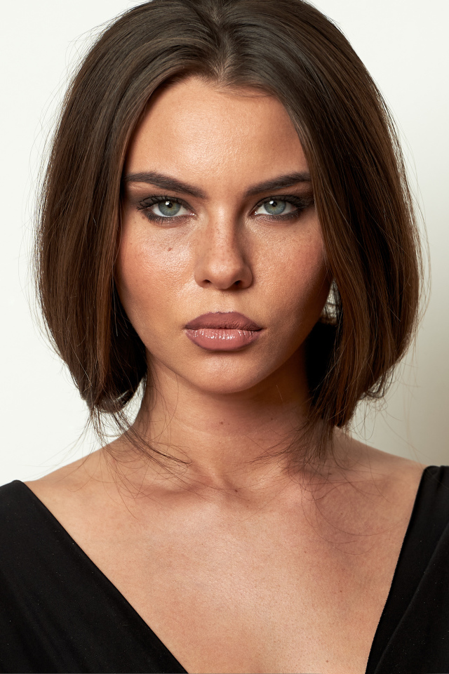 Красивая серьезная брюнетка на сером фоне