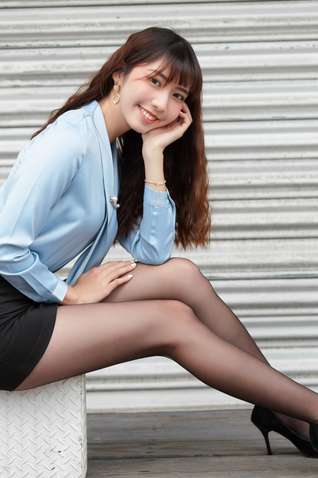 Красивая улыбающаяся девушка азиатка в черной юбке 