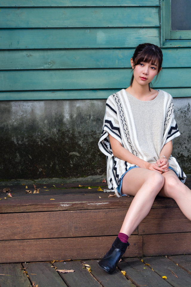 Красивая молодая девушка азиатка сидит у дома