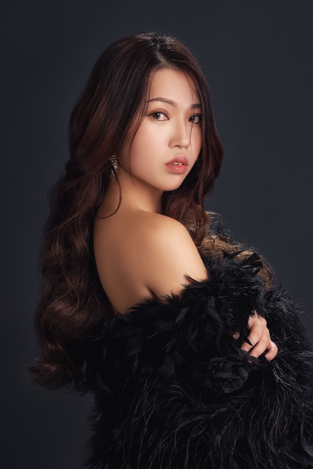 Милая девушка азиатка в черном наряде на сером фоне