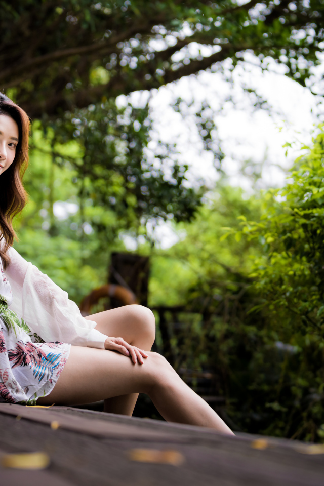 Милая девушка азиатка сидит на мосту