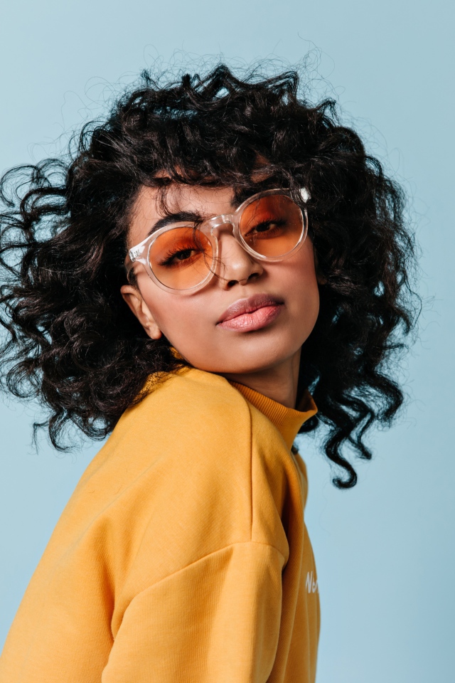 Темнокожая девушка в очках на голубом фоне фоне