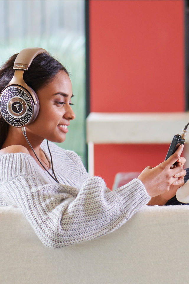 Девушка модель в наушниках на диване с плеером