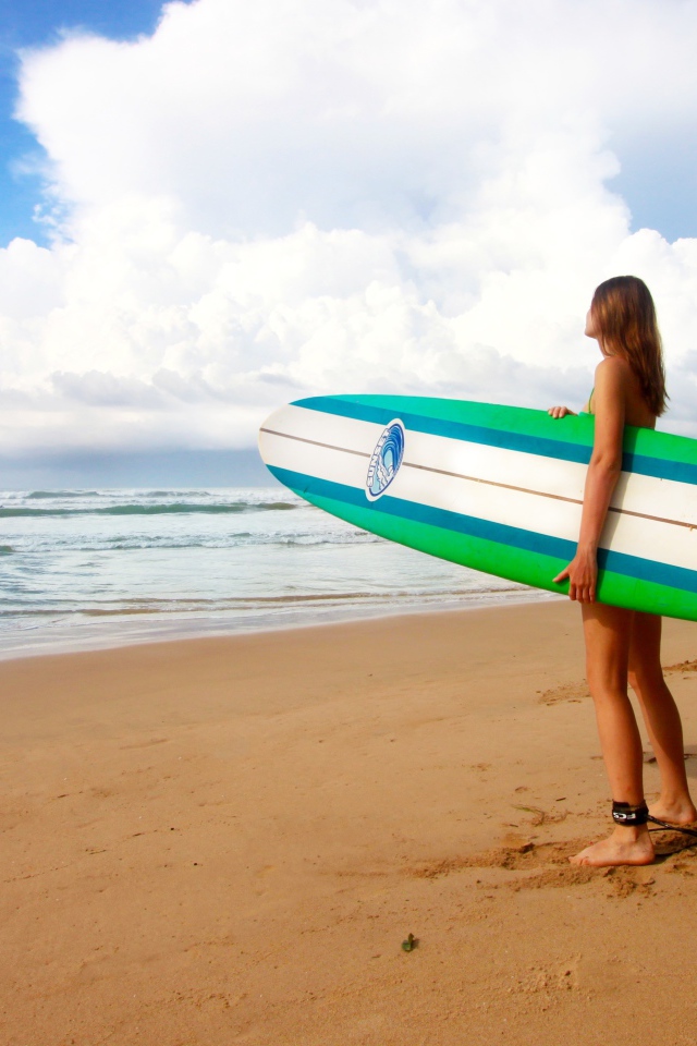 Девушка с доской для серфинга на пляже 