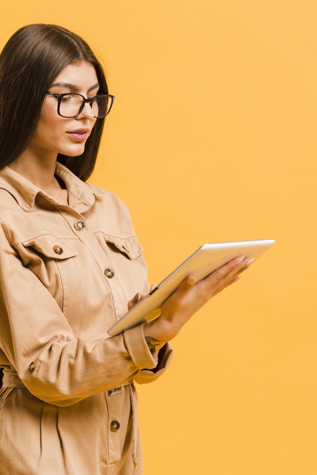 Девушка с планшетов руках на желтом фоне